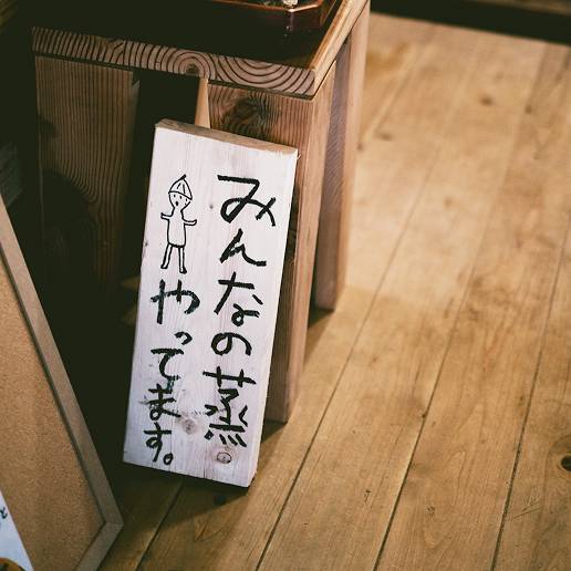 手書きでみんなの蒸やってますと書かれた木の看板の写真